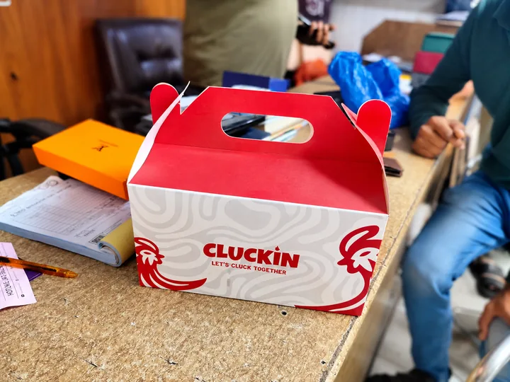 Cluckin’ branded takeaway box photographed from the front
