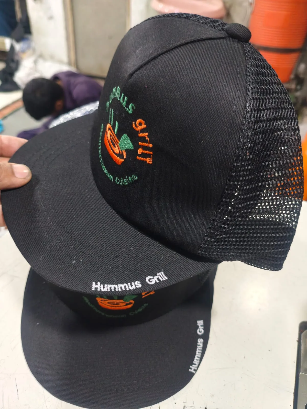 Second view of a black Hummus Grill branded cap, supplied product photo